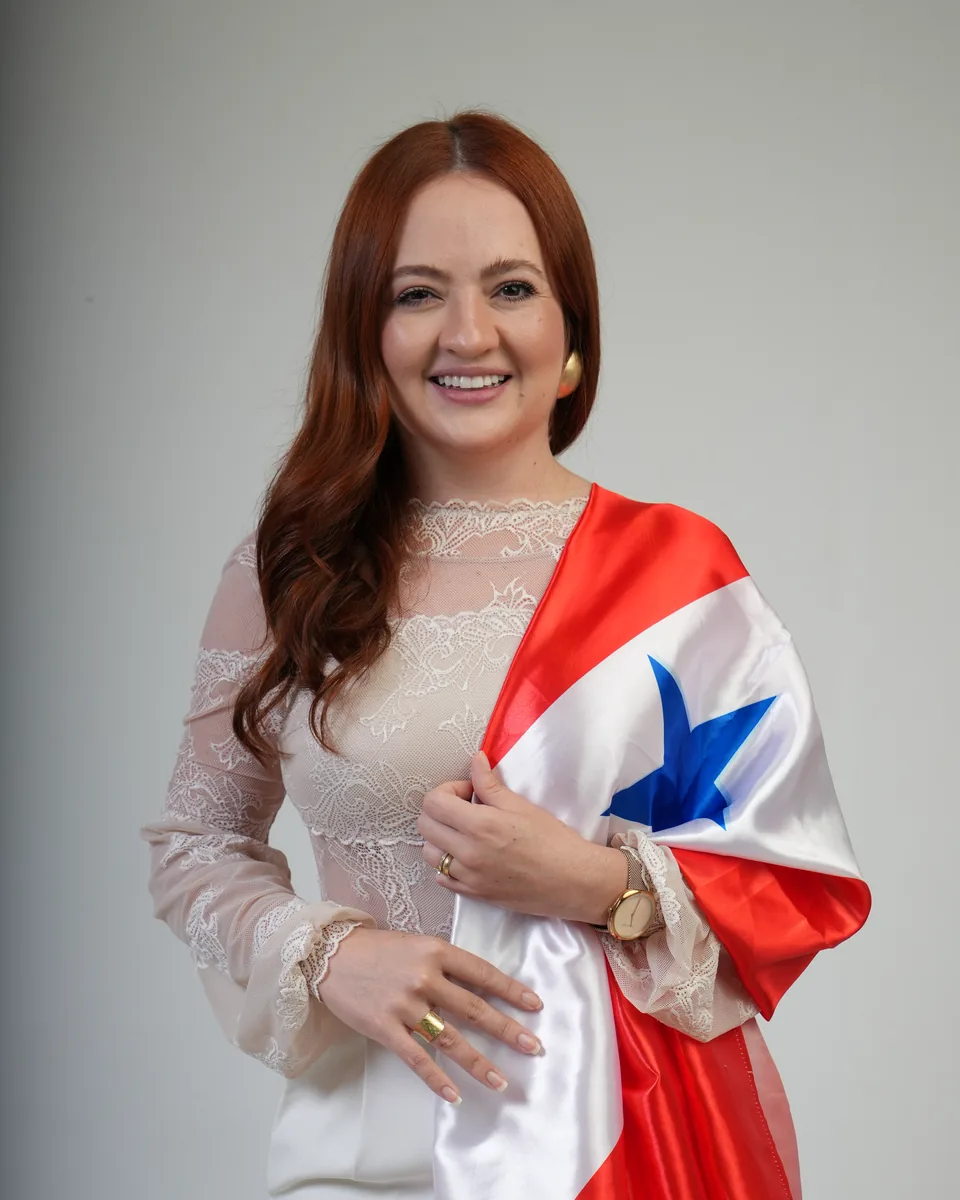 Fernanda Magalhães sorrindo, com a bandeira do Pará sobre o ombro